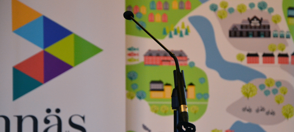 Mikrofon vid talarstol. I bakgrunden syns kommunens logotyp samt Vännäsmönstret.